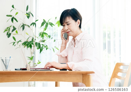 Middle-aged woman talking on smartphone in the living room Middle-aged woman talking on smartphone in the living room 126586163