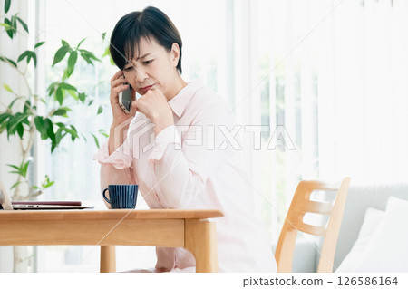 中年婦女在客廳用智慧型手機聊天 中年婦女在客廳用智慧型手機聊天 126586164