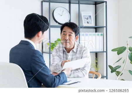 一位中年男子正在與規劃師進行諮詢 一位中年男子正在與規劃師進行諮詢 126586265