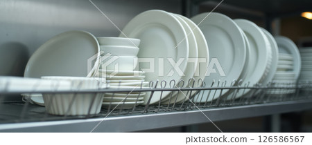 various white ceramic plates on metal shelves various white ceramic plates on metal shelves 126586567