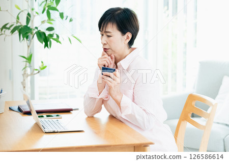 Middle-aged woman looking at a computer screen in the living room 126586614