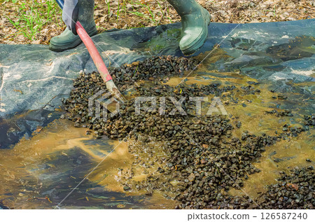 Closeup of gravel and muddy water on black tarp in forest. High quality photo Closeup of gravel and muddy water on black tarp in forest. High quality photo 126587240