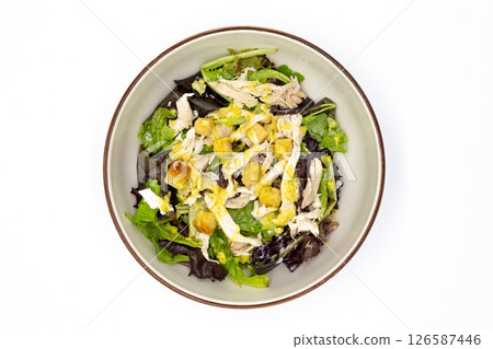 Top view of chicken salad with mixed greens shredded chicken croutons and dressing served in ceramic bowl on white background Top view of chicken salad with mixed greens shredded chicken croutons and dressing served in ceramic bowl on white background 126587446