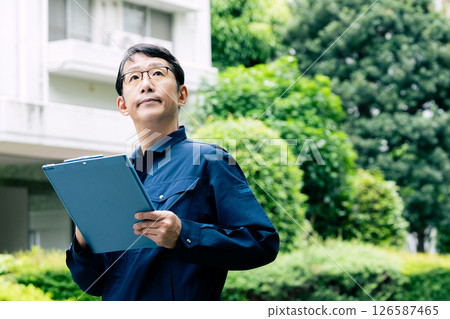 A middle-aged man inspecting equipment outdoors 126587465