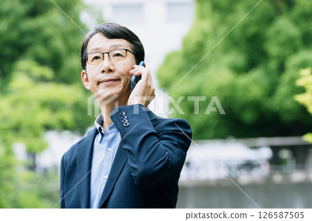 Businessman talking on smartphone outdoors Businessman talking on smartphone outdoors 126587505