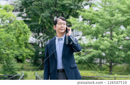 Businessman talking on smartphone outdoors 126587510