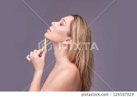 Caucasian young female examining neck contour with measuring tool on gray Caucasian young female examining neck contour with measuring tool on gray 126587929