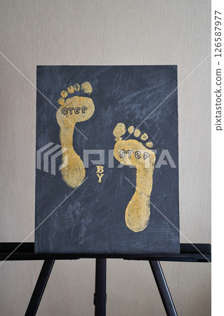 Abstract gold footprints on black canvas artwork displayed on easel 126587977