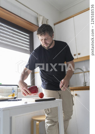 Chef placing red bell pepper and tomato on cutting board in kitchen Chef placing red bell pepper and tomato on cutting board in kitchen 126588536