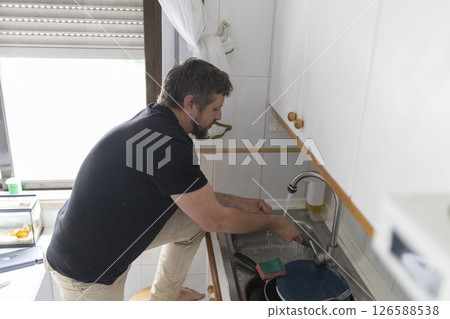 Man washing dishes in kitchen sink at home 126588538
