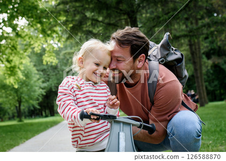 Father encourages son riding balance bike in park 126588870