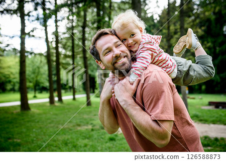 Father carrying his smiling son on shoulders during walk in park Father carrying his smiling son on shoulders during walk in park 126588873