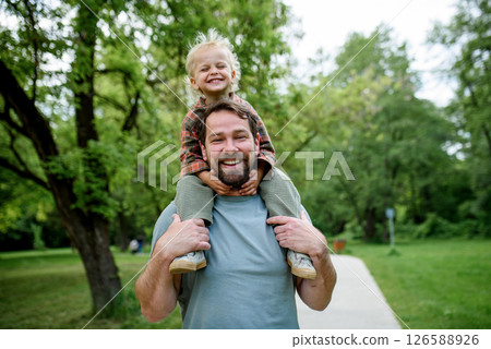 Father carrying his smiling son on shoulders during walk in park Father carrying his smiling son on shoulders during walk in park 126588926