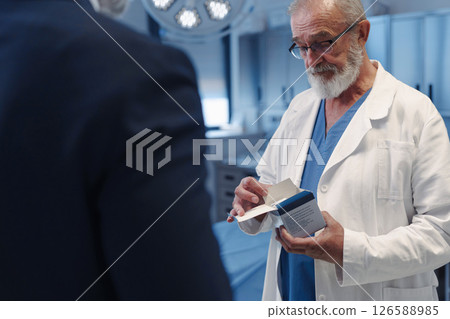 Medical sales representative introducing pharmaceutical products to doctor. Hospital setting. 126588985