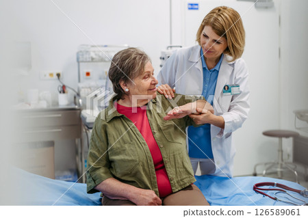 Geriatrician examining senior woman's mobility during routine check-up, Geriatrician examining senior woman's mobility during routine check-up, 126589061