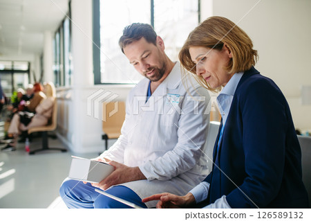 Pharmaceutical rep and doctor explaining new medication and prescriptions Pharmaceutical rep and doctor explaining new medication and prescriptions 126589132