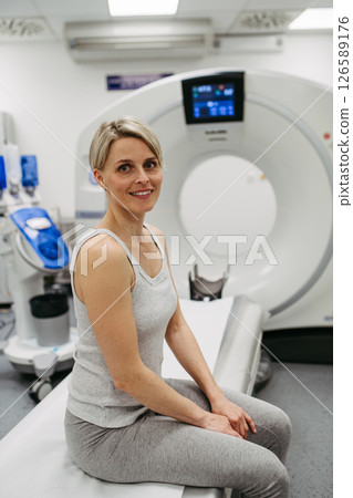Woman sitting on CT scanner bed, waiting for examination 126589176
