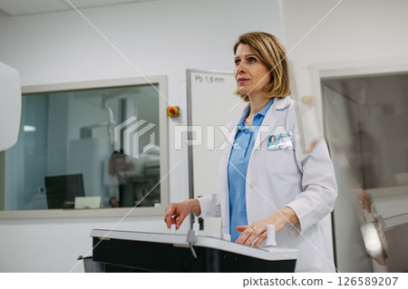 Doctor operating dynamic X-ray scan using tilting fluoroscopy unit 126589207