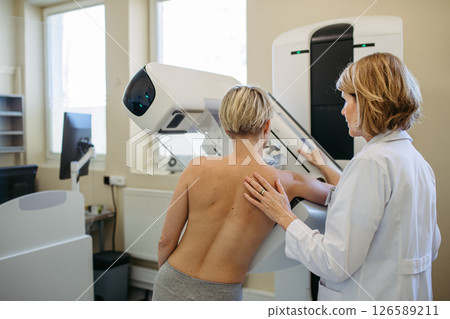 Healthcare professional adjusts the patient for proper mammogram. Healthcare professional adjusts the patient for proper mammogram. 126589211