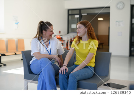 Nurse talking with teenage patient in hospital waiting room. Nurse talking with teenage patient in hospital waiting room. 126589340