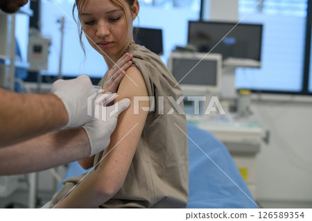 Vaccination of teenage girl during routine health checkup at hospital. 126589354