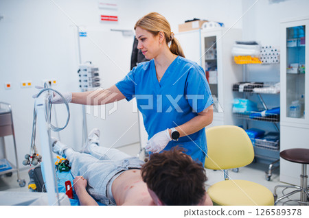 Nurse removing EKG electrodes after heart test on teenage patient. Nurse removing EKG electrodes after heart test on teenage patient. 126589378