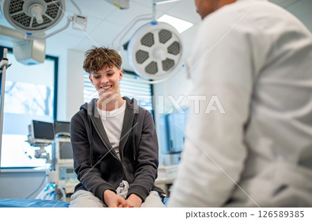 Teenage boy smiling during medical consultation after receiving positive health news. 126589385