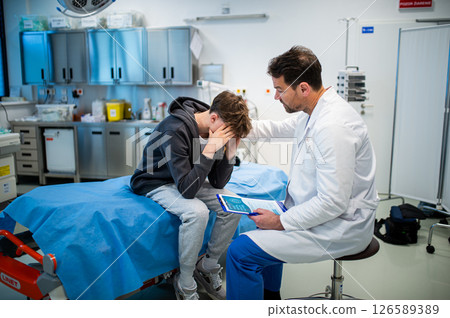 Depressed teenage patient sitting on hospital bed, talking with caring doctor. Depressed teenage patient sitting on hospital bed, talking with caring doctor. 126589389