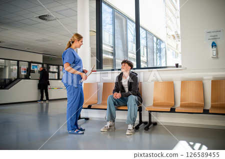 Doctor talking with teenage patient in hospital hallway. 126589455