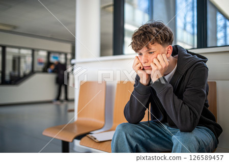 Anxious teenager waiting alone in hospital waiting area before medical checkup. Anxious teenager waiting alone in hospital waiting area before medical checkup. 126589457