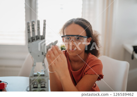 Cute girl admiring robotic hand. Cute girl admiring robotic hand. 126589462