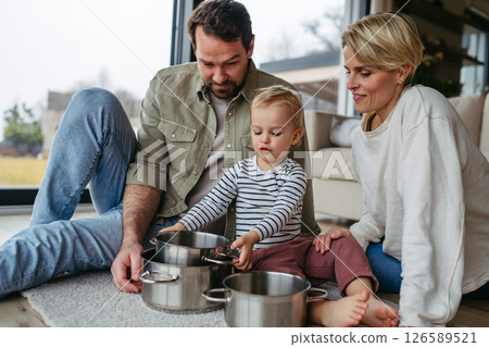 Parents and toddler son playing drums on kitchen pots Parents and toddler son playing drums on kitchen pots 126589521