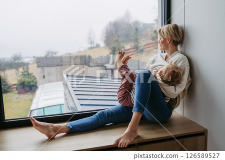 Mother breastfeeding her toddler son by the window 126589527
