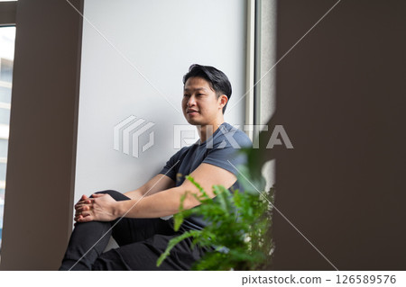 Confident young man sitting by the window in natural light 126589576