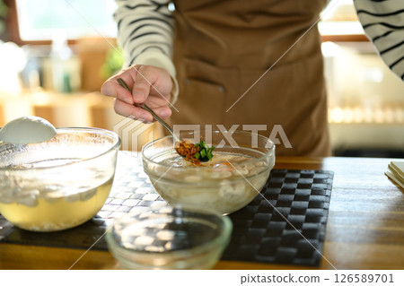 Close up of hand adding herbs and fried garlic to a bowl of hot soup Close up of hand adding herbs and fried garlic to a bowl of hot soup 126589701
