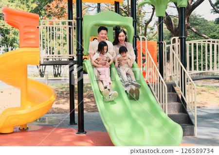 Happy family sliding down together at a colorful playground 126589734