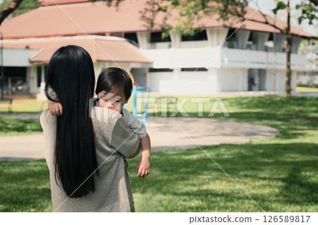 Rear view of a mom holding her toddler walking in a peaceful park 126589817