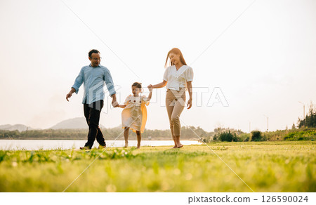 A cute Asian little girl with her mother and father walking and holding hands in a beautiful park, enjoying the nature and the season of spring, Happy family day A cute Asian little girl with her mother and father walking and holding hands in a beautiful park, enjoying the nature and the season of spring, Happy family day 126590024