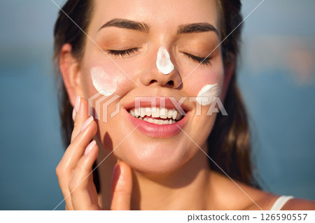 Woman smile applying sun cream on face. Skincare concept.  Body Sun protection. sunscreen. Female  smear moisturizing lotion on skin. 126590557