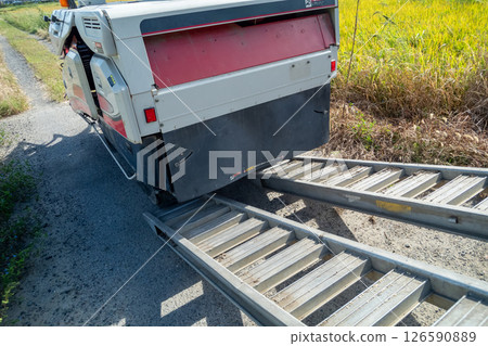 A board is hung from the truck to load and unload the combine. 126590889