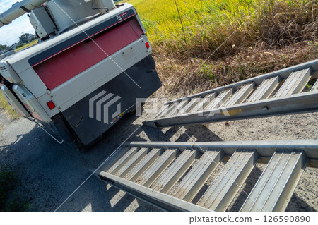 A board is hung from the truck to load and unload the combine. 126590890