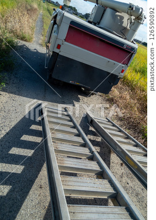 卡車上懸掛著一塊板,用於裝載和卸載聯合收割機。 卡車上懸掛著一塊板,用於裝載和卸載聯合收割機。 126590892