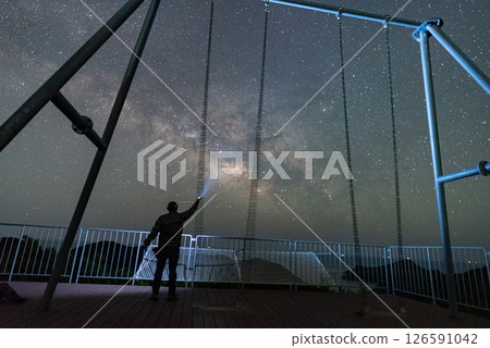 Silhouette of a person watching the stars and a swing and the beautiful Milky Way Silhouette of a person watching the stars and a swing and the beautiful Milky Way 126591042
