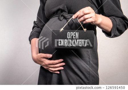 Pregnant Woman Holding Open Enrollment Sign Representing Healthcare Access and Maternity Benefits Pregnant Woman Holding Open Enrollment Sign Representing Healthcare Access and Maternity Benefits 126591450