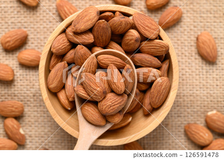 Raw almond nut seed in wooden bowl with spoon, Top view 126591478