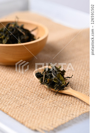 Dried green tea leaves on wooden spoon and bowl, Healthy herbal drink 126591502