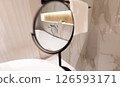 A round bathroom mirror reflecting faucet and interior in a stylish modern washroom 126593171