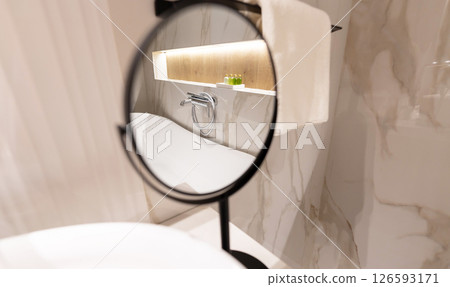 A round bathroom mirror reflecting faucet and interior in a stylish modern washroom A round bathroom mirror reflecting faucet and interior in a stylish modern washroom 126593171