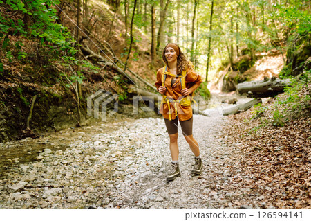 Traveler woman walking along hiking trail through forest thicket in the mountains. Active lifestyle. Traveler woman walking along hiking trail through forest thicket in the mountains. Active lifestyle. 126594141