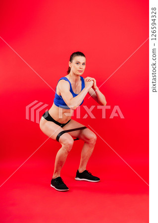 Athletic female performs exercises using a resistance band. Strength and motivation Athletic female performs exercises using a resistance band. Strength and motivation 126594328